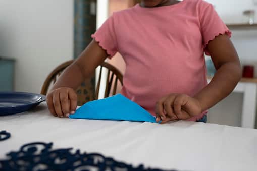 un enfant pliant une serviette en papier