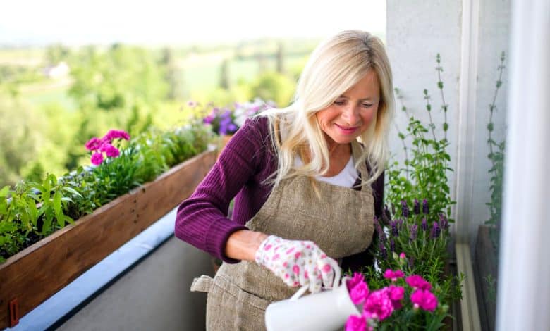 Une femme qui arrose ses plantes sur le balcon l'été