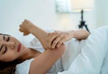 Femme se gratte la main dans son lit
