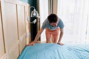 Homme mettant un couvre-matelas sur le lit