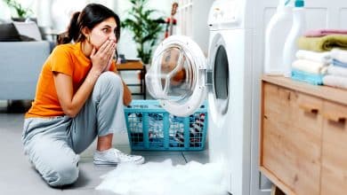 Une femme qui examine sa machine à laver et cherche du calcaire
