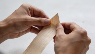 artisan poncant une fine feuille de placage bois