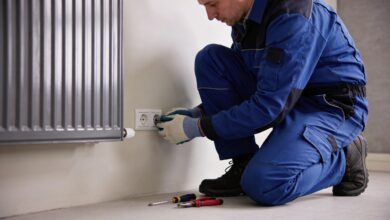 Electricien accroupi changeant prise murale vers radiateur