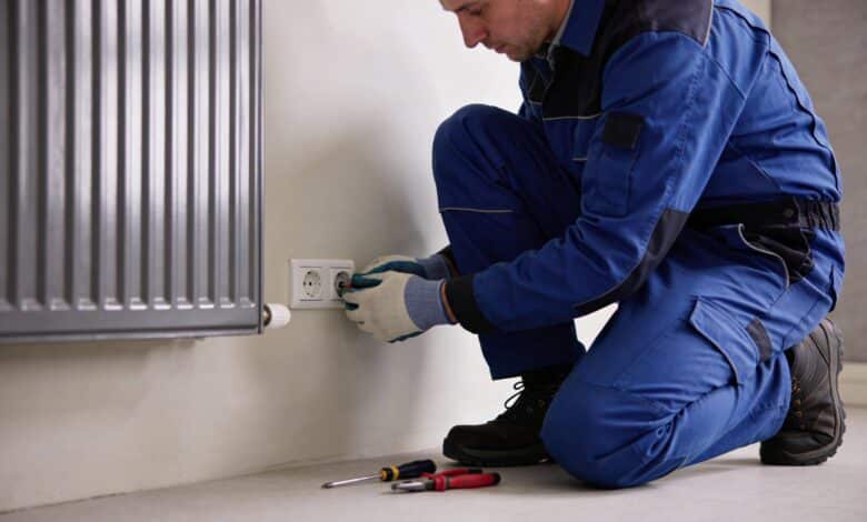 Electricien accroupi changeant prise murale vers radiateur