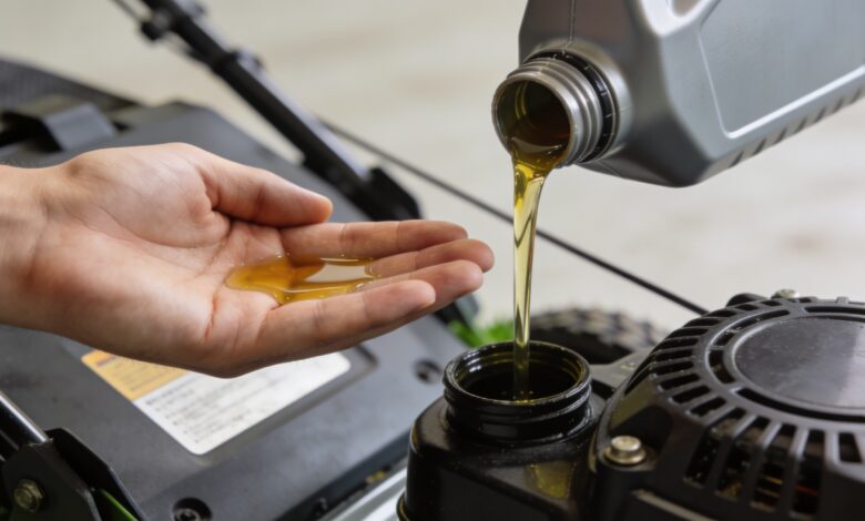 gros plan sur main versant huile moteur tondeuse