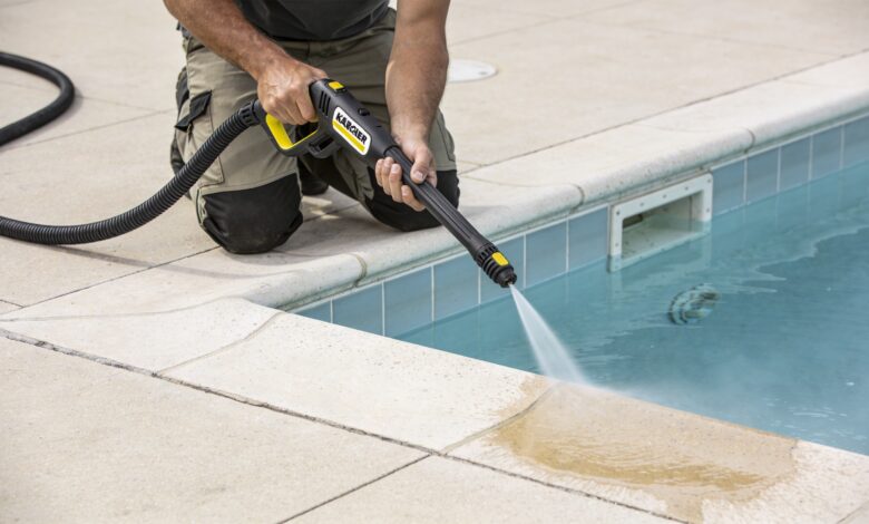 Homme agenouille nettoyant margelle de piscine au karcher