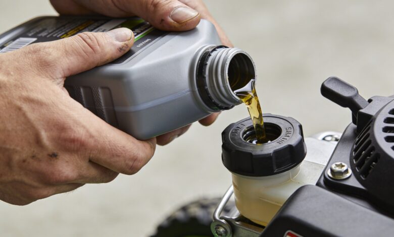 mains versant huile moteur dans petite tondeuse