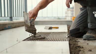 ouvrier agenouille versant mortier sur terrasse avant carrelage
