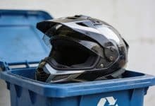 Casque de motocyclette posé dans bac recyclage bleu.