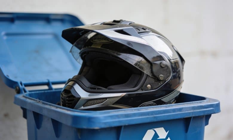 Casque de motocyclette posé dans bac recyclage bleu.