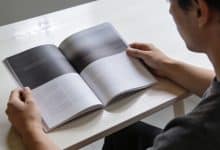 Personne consultant un journal ou magazine sur table claire.