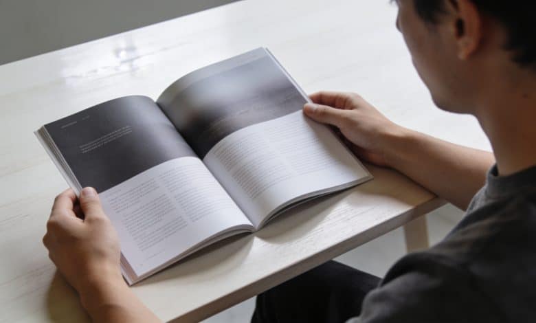Personne consultant un journal ou magazine sur table claire.