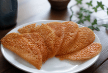 Tuiles croquantes dorées disposées en eventail sur assiette blanche.