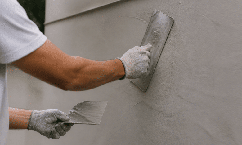 Mains appliquant revetement lisse gris sur surface murale avec spatule