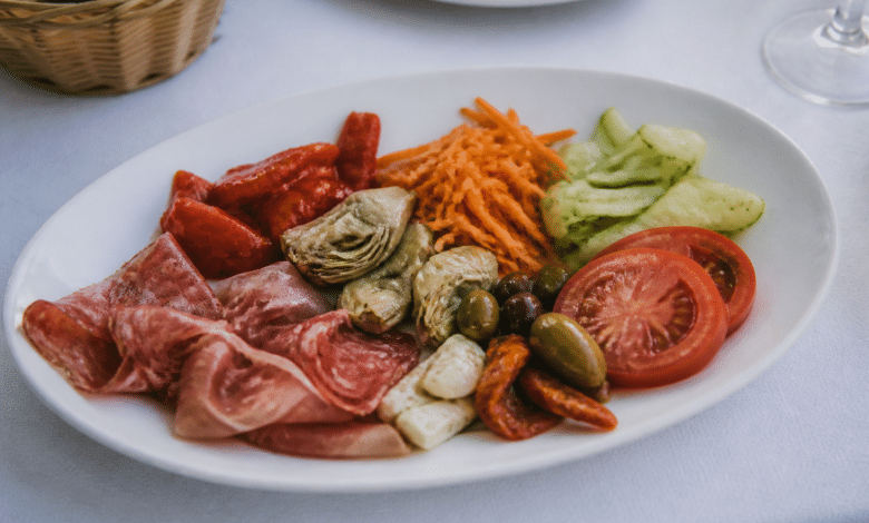 Assiette froide garnie de legumes et charcuterie disposee sur table blanche