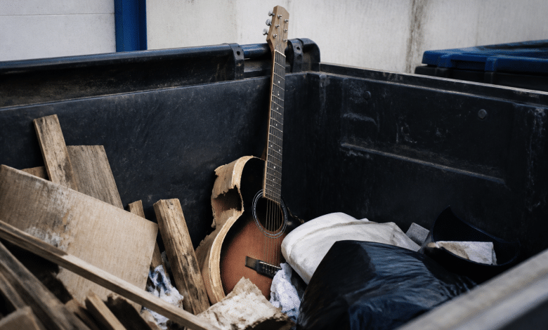 Guitare cassee posee verticalement dans benne dechets