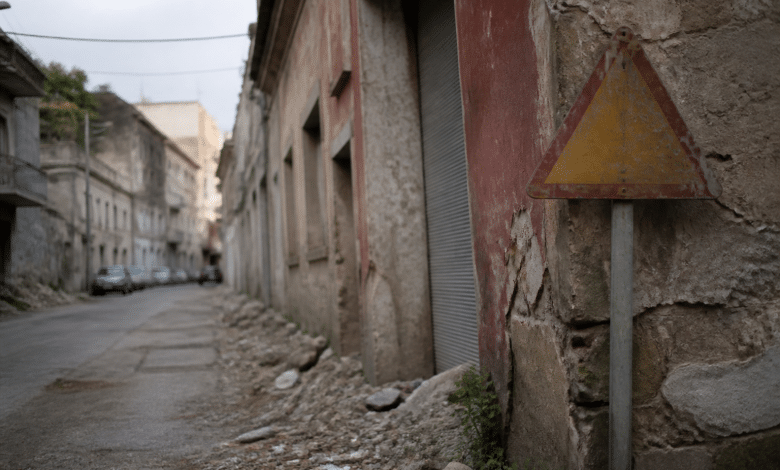 Rue urbaine avec batiments degrades et panneau d'avertissement visible