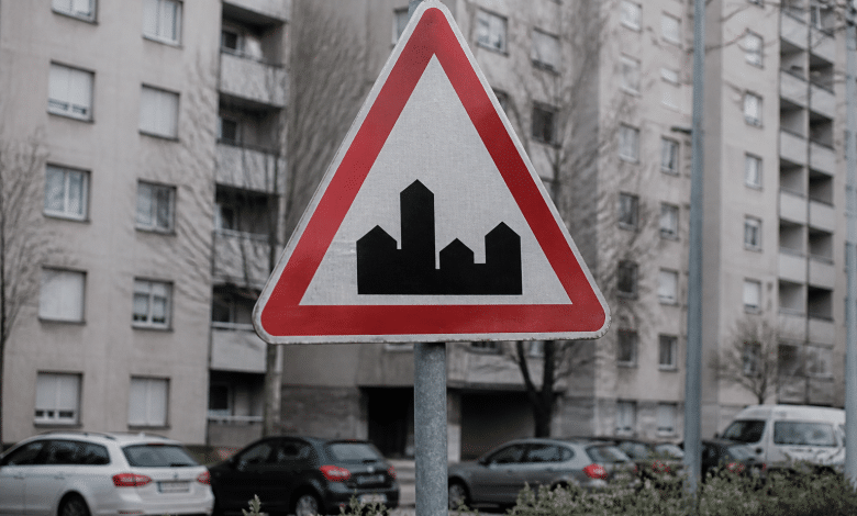 Panneau routier indiquant zone urbaine densifiee avec immeubles gris en arriere-plan